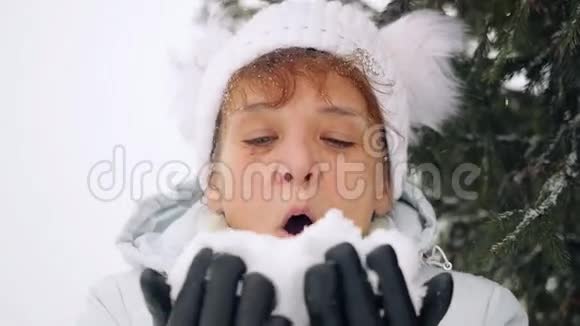 成熟的快乐的女人在冬天在公园里缓慢地吹雪花1920x1080视频的预览图