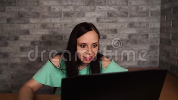 年轻女性使用笔记本电脑坐在白色砖墙背景前人和技术生活方式视频的预览图