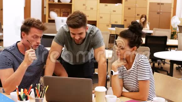 男性和女性商务主管在办公桌上讨论笔记本电脑视频的预览图