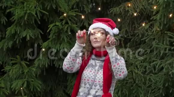 在圣诞树和花环的背景上年轻的女人用闪闪发光的东西视频的预览图