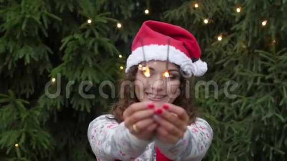 在圣诞树和花环的背景上年轻的女人用闪闪发光的东西视频的预览图