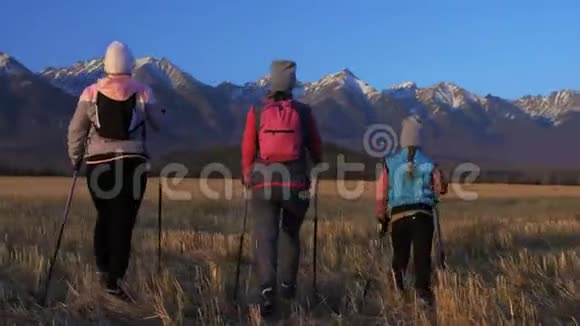 女人在大自然中行走在田野的群山背景下女孩和孩子使用跋涉棒和北欧视频的预览图