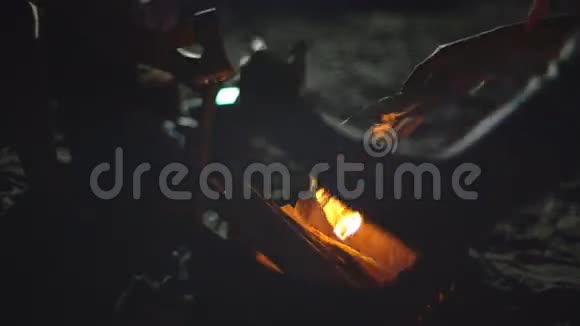 一只雄性手在点燃的火焰下握着一块木头来发动一场营火视频的预览图