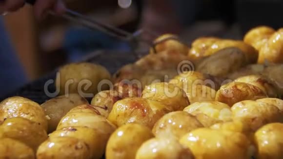 年轻的土豆在烤架上准备手用火钳在烤肉上烤土豆视频的预览图