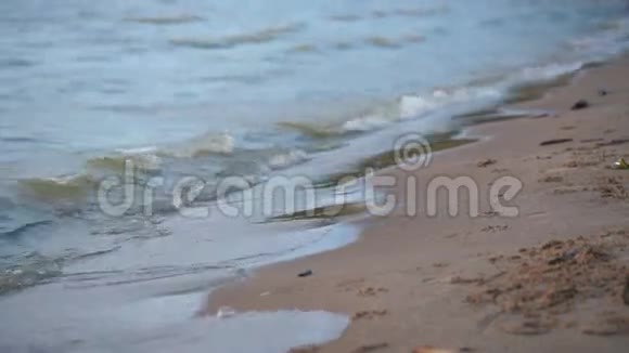 靠近海浪柔和的海浪在日落时的沙滩上冲着阳光反射视频的预览图