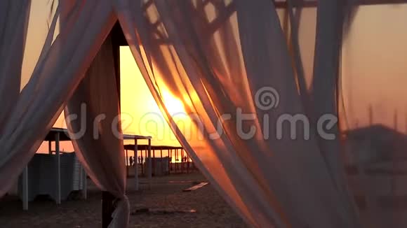 海边的沙滩上的露台沙滩窗帘在风中摇曳视频的预览图