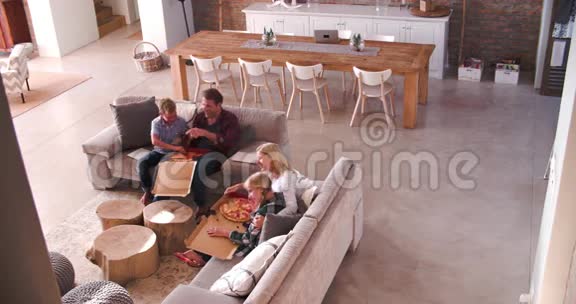 坐在沙发上吃披萨的家庭俯视图视频的预览图
