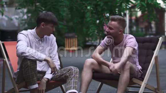 两个男孩坐在街上的椅子上视频的预览图