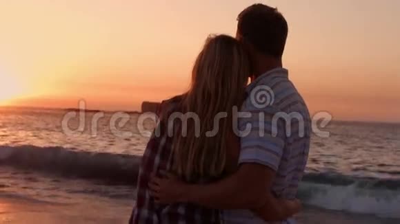 可爱的情侣在海滩上的日落时拥抱视频的预览图