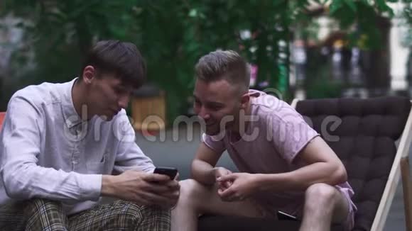 两个男孩坐在街上的椅子上视频的预览图