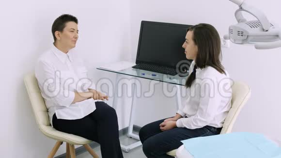 牙医在牙医诊所和年轻的女性病人交谈视频的预览图
