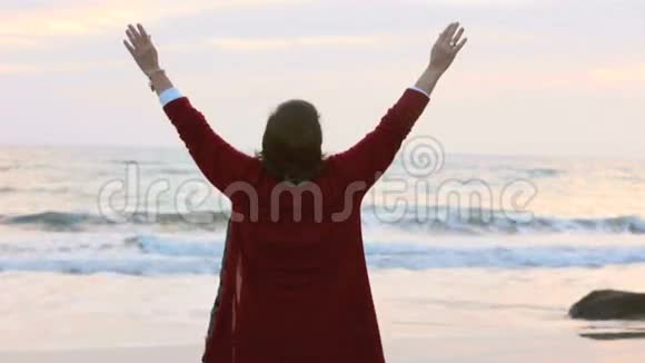 日落时分女人沿着海滩散步伸展手臂视频的预览图