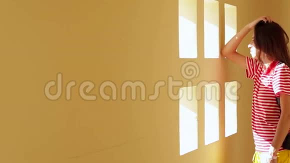美丽的黑发年轻女子站在靠近白色墙壁和小窗户视频的预览图
