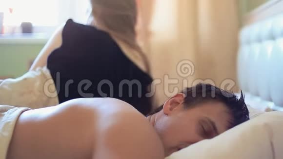 女孩醒来后在床上和熟睡的肌肉发达的丈夫交谈清晨视频的预览图