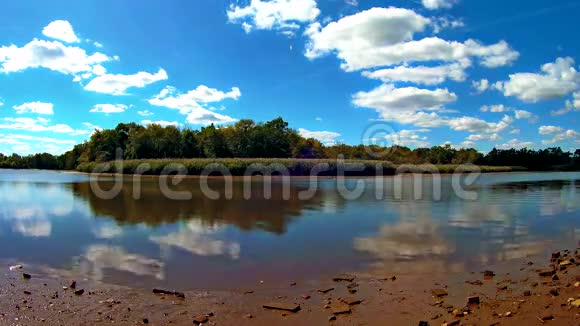 平静的一天在湖边天空树和云在湖水上倒影视频的预览图