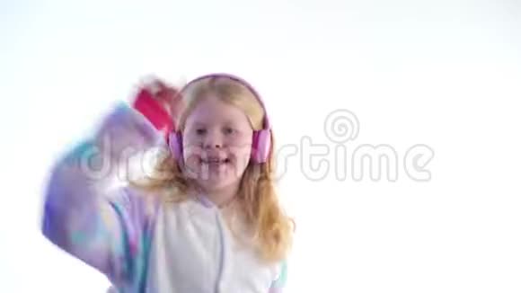 现代时尚美丽的金发女孩听音乐带着耳机在基古鲁米的白色背景下跳舞视频的预览图