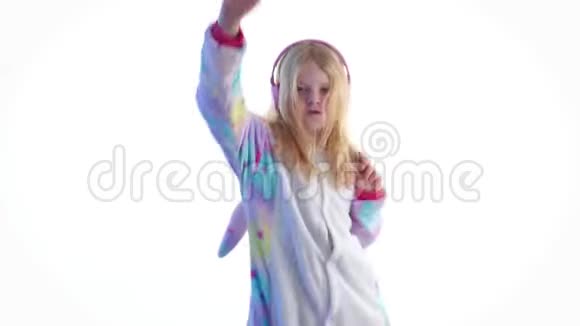 现代时尚美丽的金发女孩听音乐带着耳机在基古鲁米的白色背景下跳舞视频的预览图