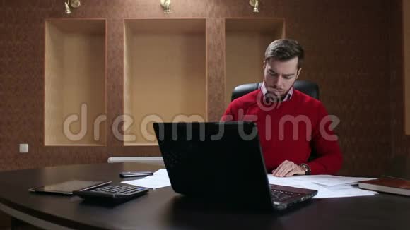 商人在桌上用商务文件和笔记本电脑工作视频的预览图