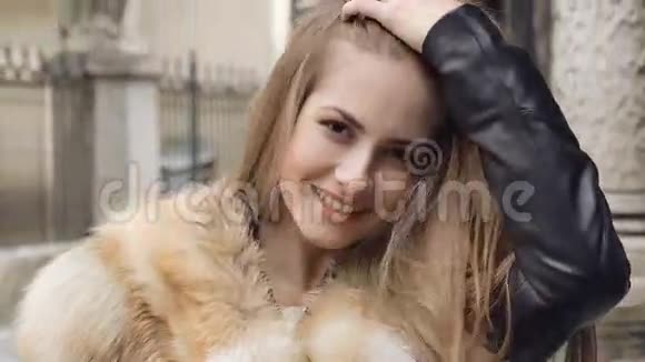 穿着毛茸茸的夹克在街上摆姿势的可爱女孩视频的预览图