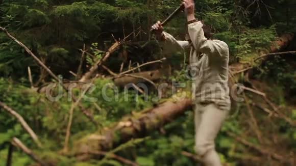 在喀尔巴阡山的绿色森林里穿着传统服装的年轻乡下樵夫在砍柴视频的预览图