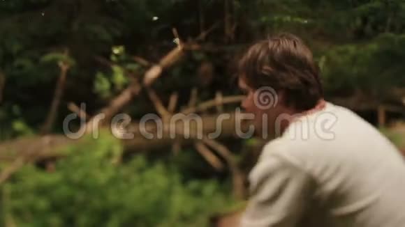 在喀尔巴阡山的绿色森林里穿着传统服装的年轻乡下樵夫在砍柴视频的预览图