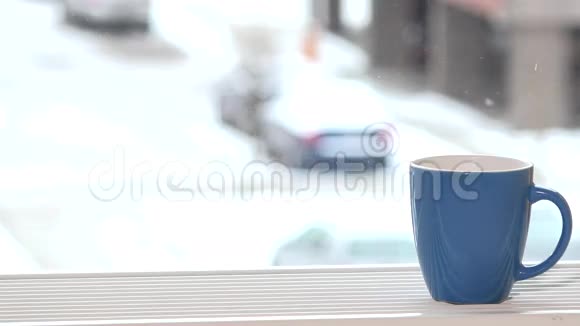 一杯咖啡茶热饮窗台上雪花飘落户外视频的预览图