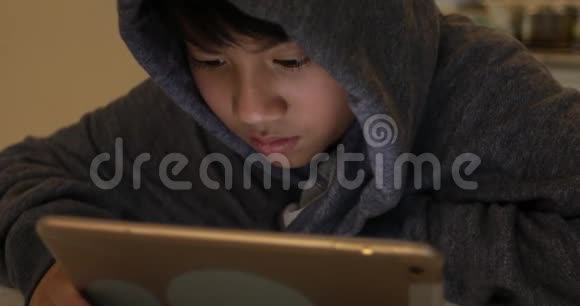 可爱的亚洲男孩使用平板电脑年轻的十几岁男孩在数字平板电脑上玩游戏带着微笑的脸视频的预览图