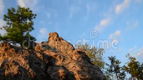 岩石上的松树背景上美丽的多云天空视频的预览图