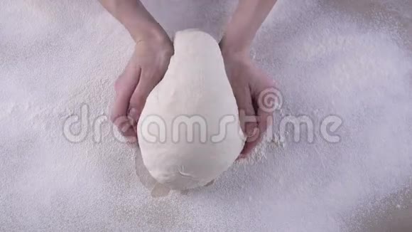 女人用手捏着装满面粉的木桌上的面团视频的预览图