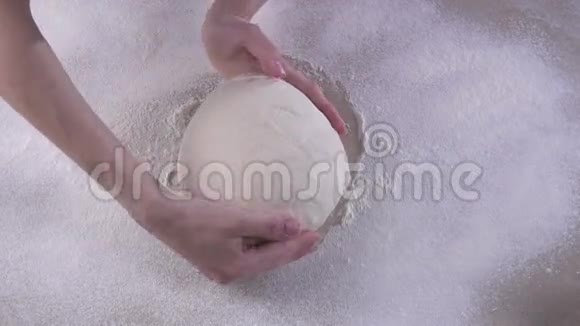 女人用手捏着装满面粉的木桌上的面团视频的预览图