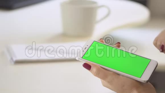 使用智能手机观看绿色屏幕的妇女在手机上浏览色度键在线阅读社交媒体视频的预览图