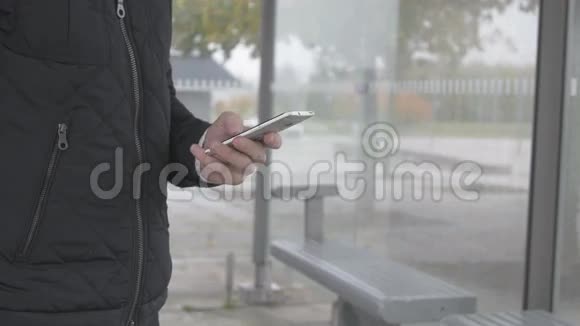 一名男子在公共汽车站使用智能手机的特写镜头视频的预览图