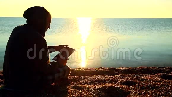 一个拿着石碑的人坐在海边的沙砾滩上视频的预览图