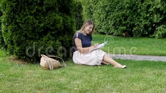 坐在公园里写日记的年轻女子视频的预览图