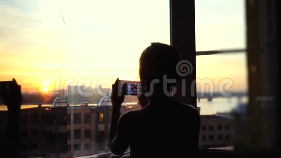 年轻女子在家门口的手机上拍摄城市照片3840x2160视频的预览图