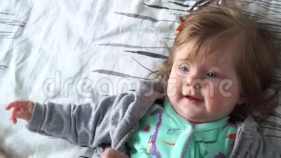 可爱的女婴躺在床上微笑视频的预览图