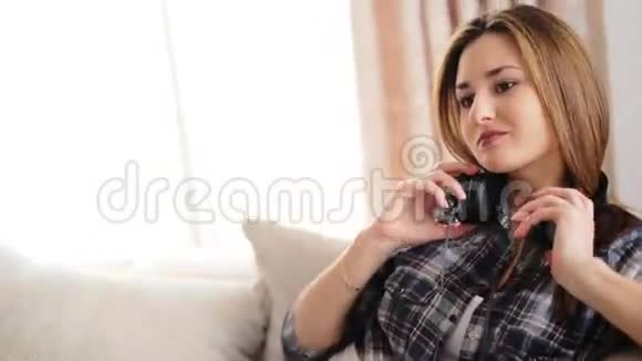 年轻漂亮的女人躺在沙发上在客厅的耳机里听音乐视频的预览图