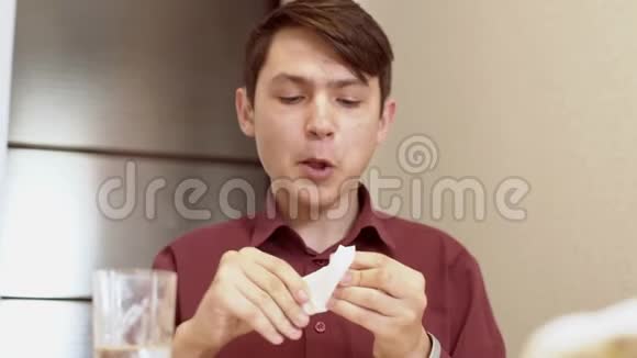 一个15岁的青少年咬一个三明治一个年轻人在桌子上吃三明治视频的预览图