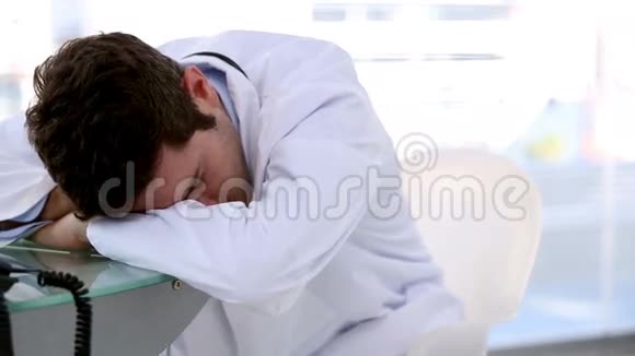 年轻的医生睡在桌子上视频的预览图