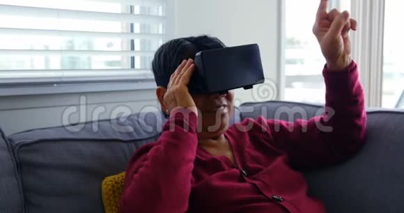 使用虚拟现实耳机的高级女性客厅视频的预览图