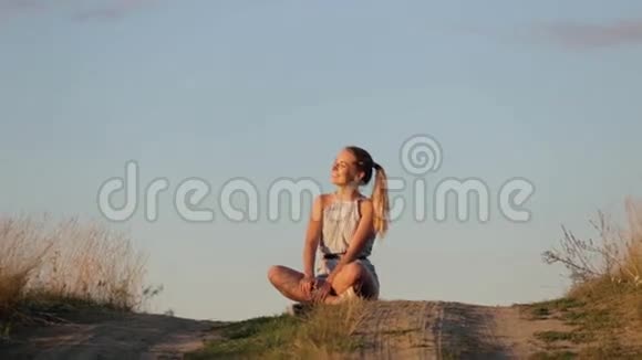 美丽的少女在夕阳的照耀下在山上沉思视频的预览图