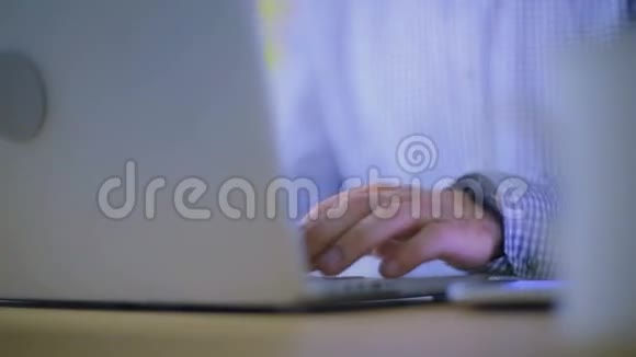 在笔记本电脑后面的办公室里工作的人的双手特写视频的预览图