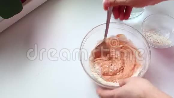 一个男人正在做古拉什酱用勺子将番茄酱酸奶油和面粉放入玻璃容器中搅拌加水再混合视频的预览图
