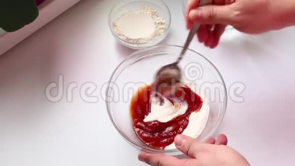 一个男人正在做古拉什酱用勺子把番茄酱和酸奶油放入玻璃容器中搅拌视频的预览图
