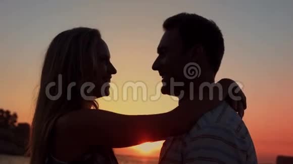 可爱的情侣在海滩上的日落时拥抱视频的预览图