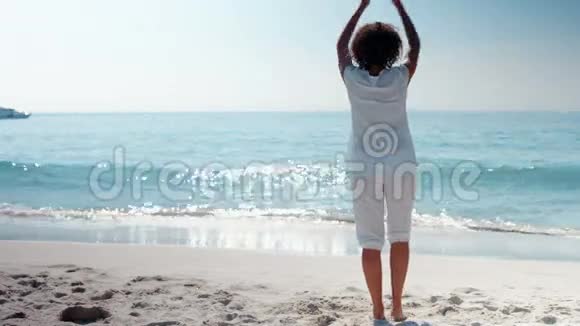 穿着女人在海滩上做瑜伽的风景视频的预览图