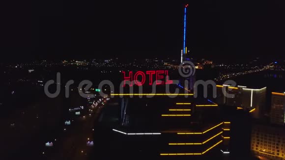 艾琳霓虹灯红色铭文酒店在夜间城市的一座现代建筑的屋顶上旁边是交通车视频的预览图