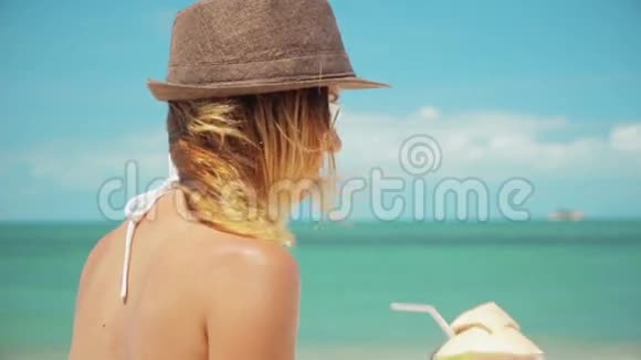 女人喝着新鲜的椰子水和稻草海滩有趣的假期视频的预览图