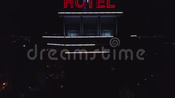 空中夜城一栋现代化建筑屋顶上的霓虹红色铭文酒店旁边是交通车视频的预览图