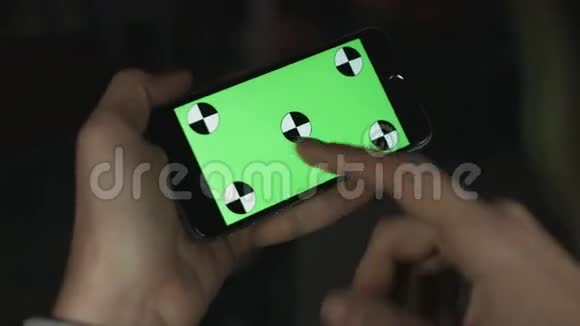 智能手机用手拿着绿色屏幕Chroma键快关门跟踪运动卧式裤子向左向右滑动视频的预览图